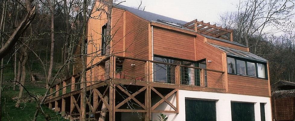 Maison en ossature bois sur trois niveaux, bardage en bois naturel, terrasse, balcon, pergola, baies vitrées.